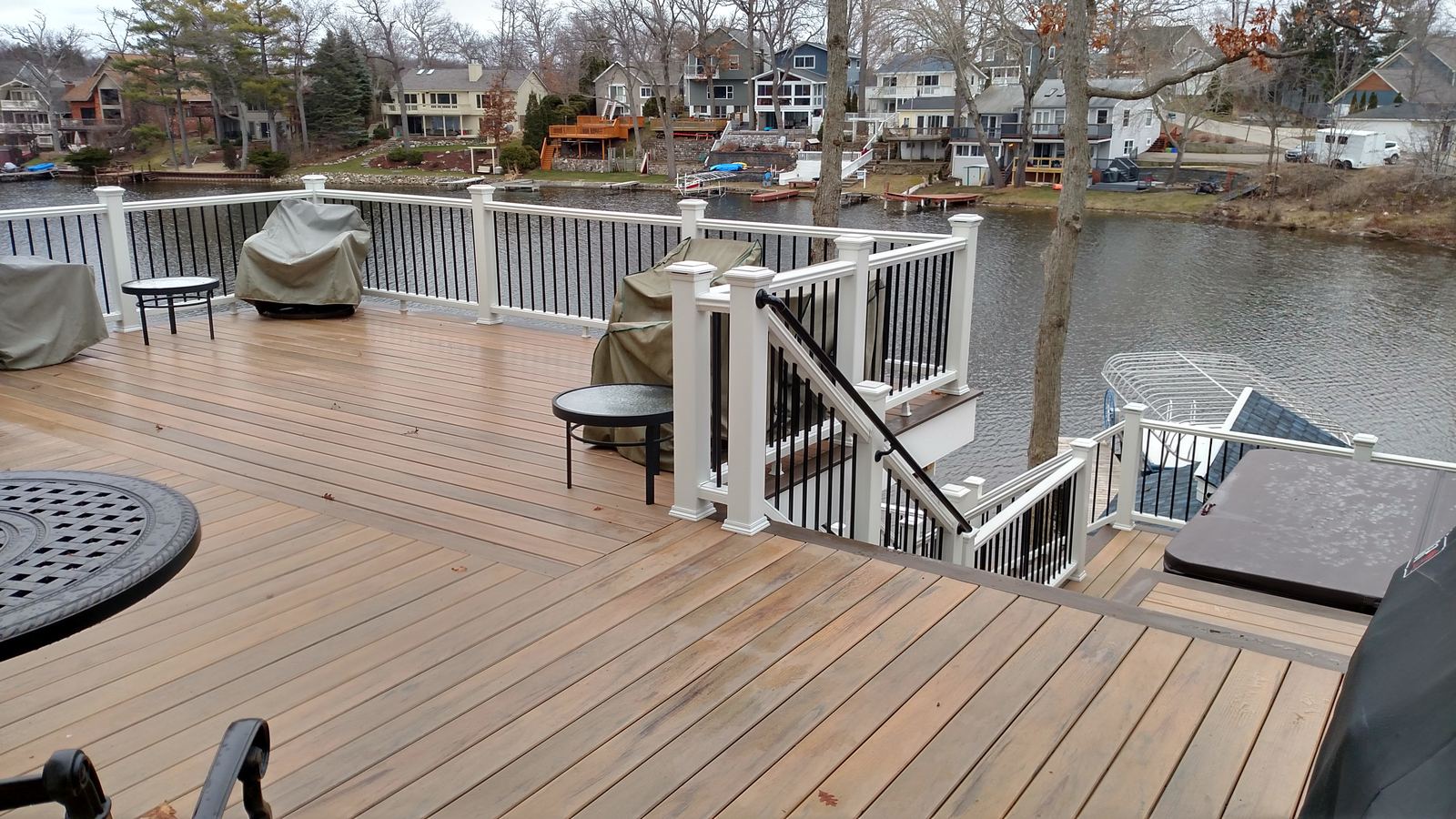 Composite deck with white railings overlooking a Michigan lake, built by Supreme Deck